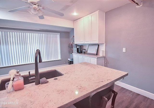 kitchen with a breakfast bar, sink, white cabinetry, dark hardwood / wood-style flooring, and ceiling fan