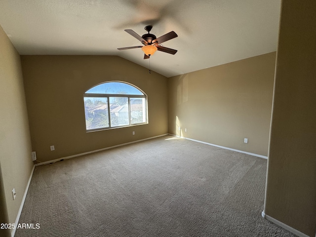 carpeted spare room with ceiling fan, baseboards, and vaulted ceiling