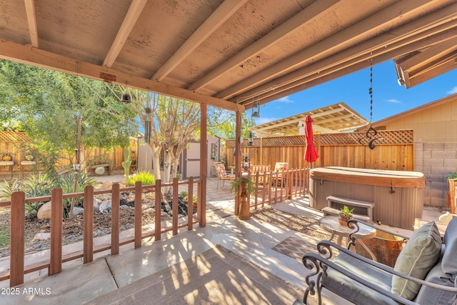 view of patio / terrace with a hot tub and a storage unit