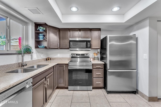 kitchen with sink, stainless steel appliances, a raised ceiling, dark brown cabinets, and light tile patterned flooring