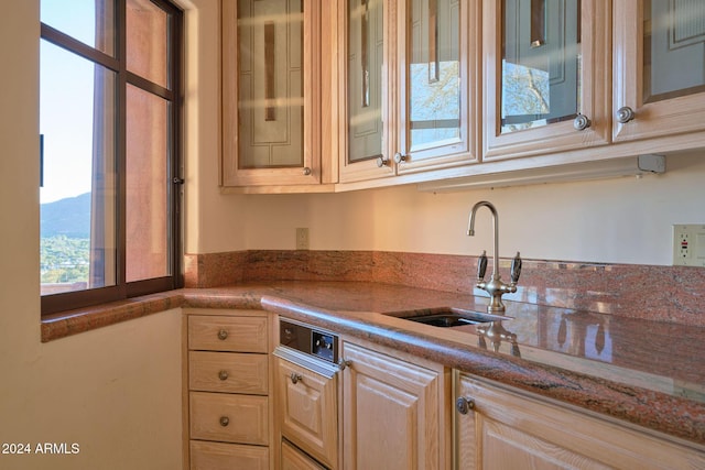 kitchen with sink, stone countertops, and light brown cabinets