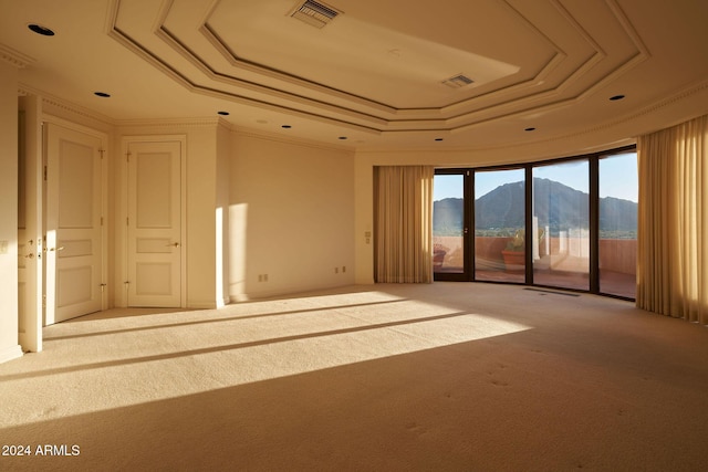 unfurnished room featuring a mountain view, carpet floors, crown molding, and a tray ceiling