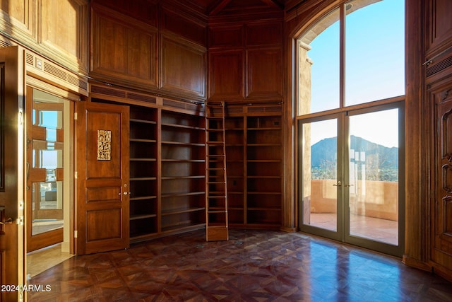 empty room with a mountain view, a towering ceiling, a wealth of natural light, and wood walls