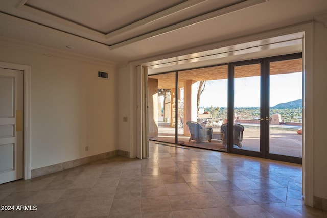 empty room with a mountain view, french doors, a raised ceiling, and ornamental molding