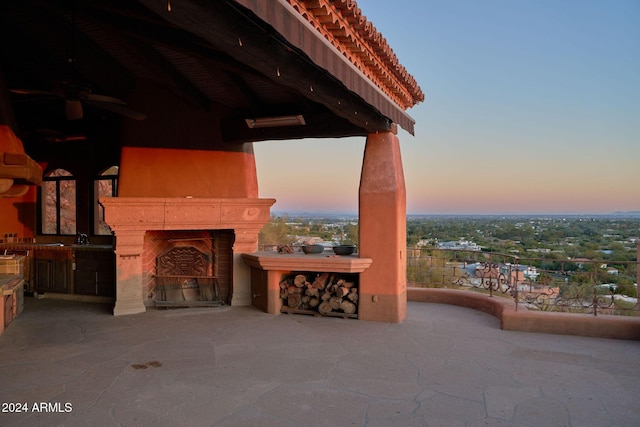 patio terrace at dusk with sink and an outdoor fireplace