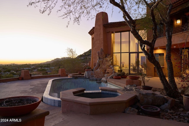 pool at dusk with a mountain view and a patio