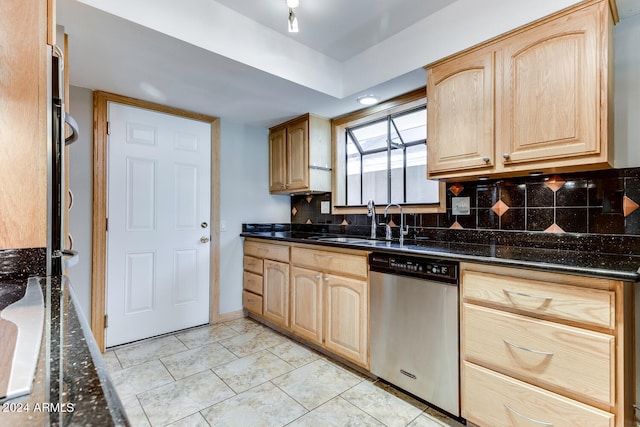 kitchen with dark stone countertops, light brown cabinetry, and stainless steel dishwasher