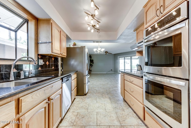 kitchen featuring appliances with stainless steel finishes, a notable chandelier, pendant lighting, light brown cabinets, and sink