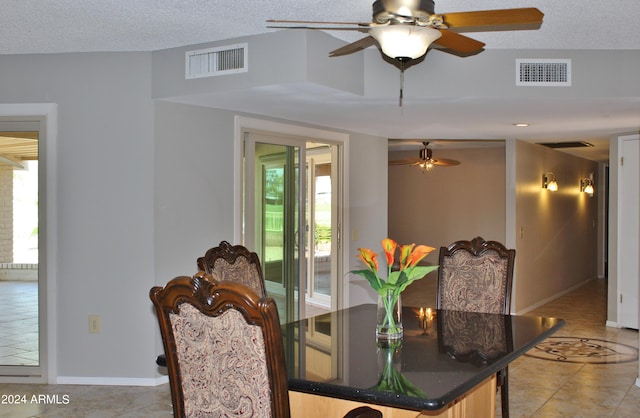 tiled dining area with ceiling fan and a textured ceiling