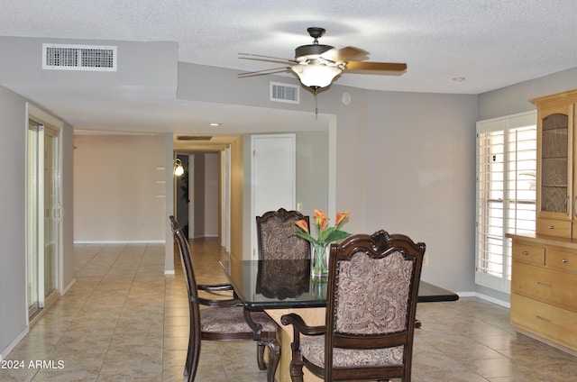 dining space with light tile patterned flooring, ceiling fan, and a textured ceiling