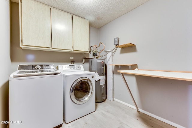 clothes washing area featuring cabinets, independent washer and dryer, electric water heater, and light hardwood / wood-style flooring