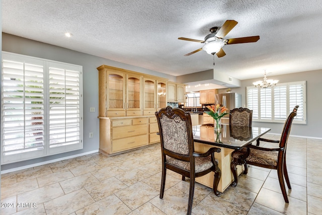 dining room with ceiling fan with notable chandelier and a textured ceiling