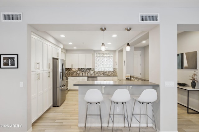 17850 N 68th St Unit 2138, Phoenix, AZ 85054 - kitchen with appliances with stainless steel finishes, light wood-style floors, a peninsula, a breakfast bar area, and recessed lighting