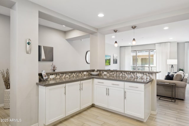17850 N 68th St Unit 2138, Phoenix, AZ 85054 - kitchen featuring dark countertops, open floor plan, white cabinets, light wood-style flooring, and a peninsula