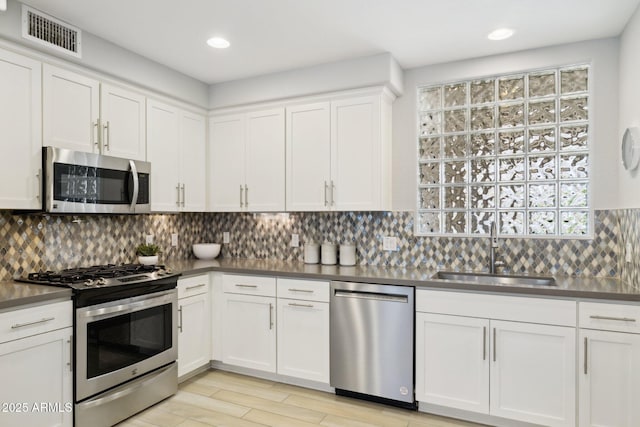 17850 N 68th St Unit 2138, Phoenix, AZ 85054 - kitchen with stainless steel appliances, a sink, white cabinets, backsplash, and light wood finished floors