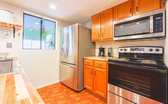 kitchen with sink, light parquet flooring, and appliances with stainless steel finishes