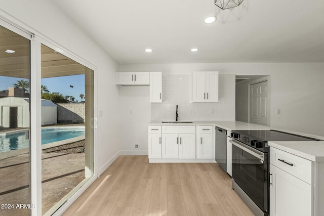 kitchen featuring white cabinets, sink, light hardwood / wood-style flooring, decorative backsplash, and appliances with stainless steel finishes