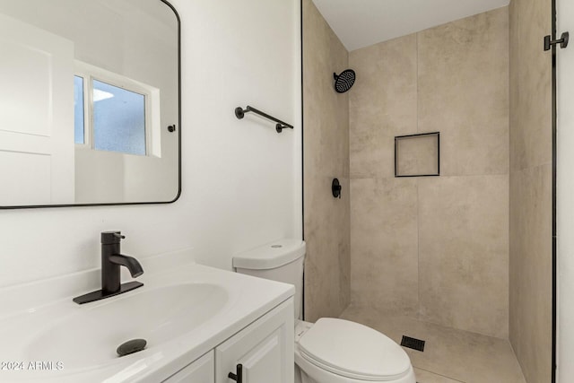 bathroom with a tile shower, vanity, and toilet