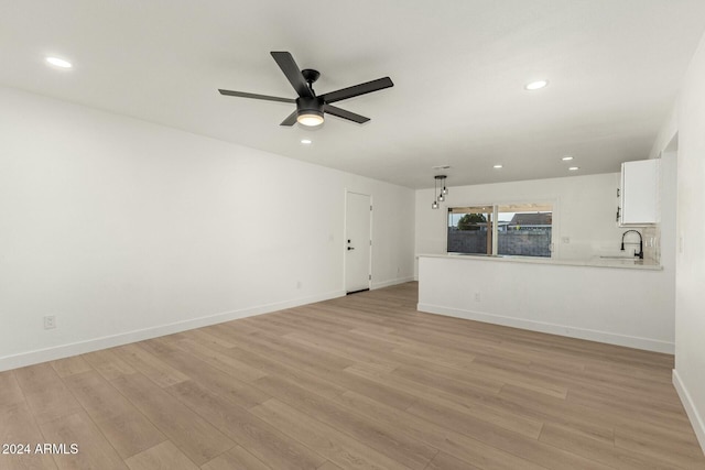 unfurnished living room with ceiling fan, light hardwood / wood-style flooring, and sink