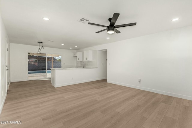 unfurnished living room with light hardwood / wood-style floors, ceiling fan, and sink