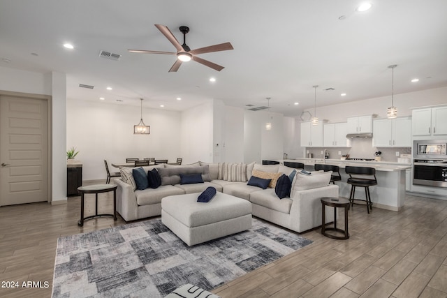 living room with ceiling fan and light hardwood / wood-style flooring