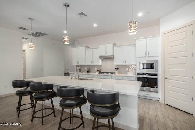 kitchen featuring appliances with stainless steel finishes, an island with sink, and pendant lighting