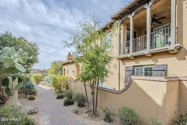 exterior space featuring ceiling fan, a balcony, and stucco siding