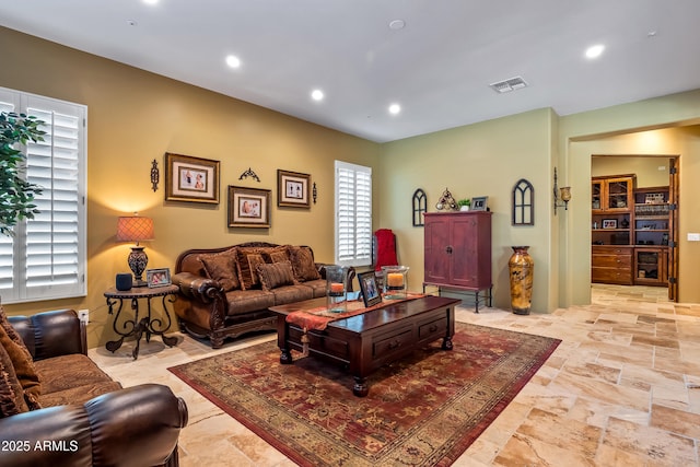 living room featuring recessed lighting, stone finish flooring, and visible vents