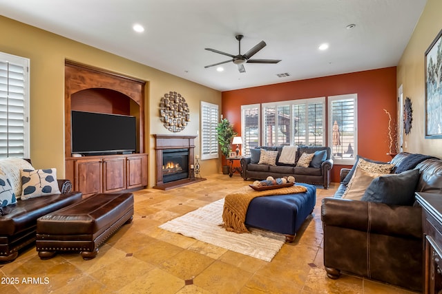 living room featuring ceiling fan, a glass covered fireplace, visible vents, and recessed lighting