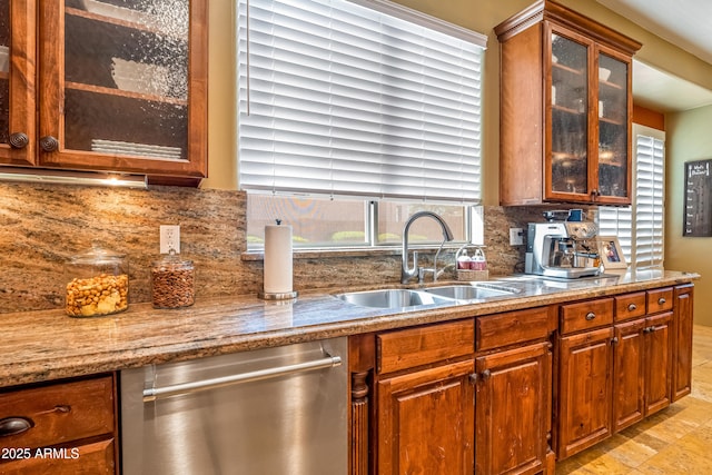 kitchen featuring glass insert cabinets, a sink, stainless steel dishwasher, and tasteful backsplash