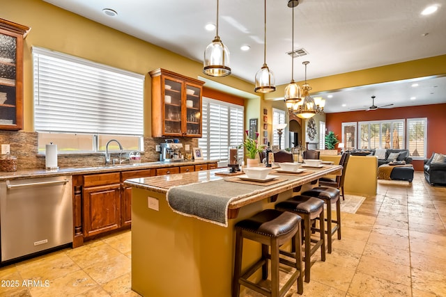 kitchen with stainless steel dishwasher, glass insert cabinets, open floor plan, a kitchen island, and a kitchen breakfast bar