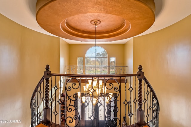 stairs featuring a chandelier and a raised ceiling