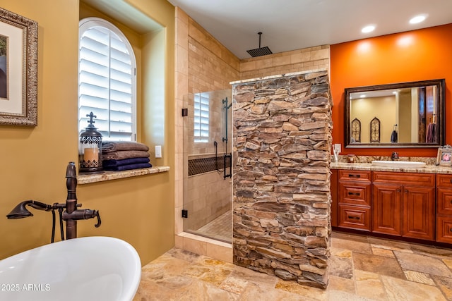 bathroom featuring a stall shower, stone tile floors, a soaking tub, vanity, and recessed lighting