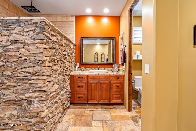 bathroom featuring visible vents, toilet, stone tile flooring, vanity, and recessed lighting