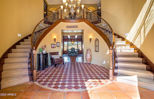 entrance foyer featuring tile patterned flooring, visible vents, a towering ceiling, stairway, and an inviting chandelier