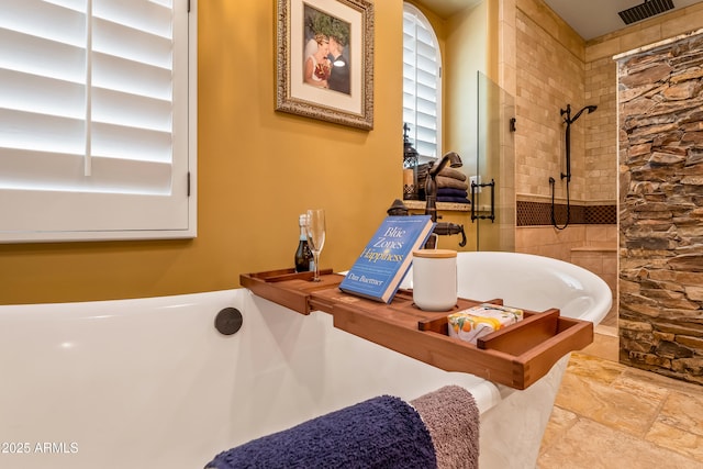 bathroom featuring tiled shower, a freestanding bath, and visible vents