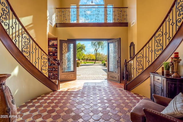 entrance foyer featuring stairs, a high ceiling, visible vents, and tile patterned floors