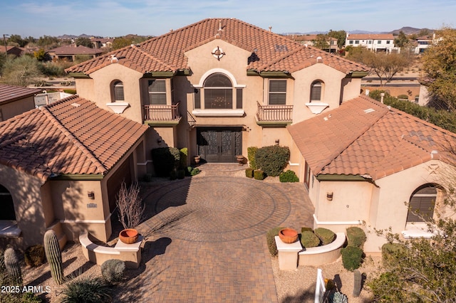 mediterranean / spanish house featuring a residential view, decorative driveway, a tile roof, and stucco siding