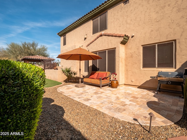 back of house featuring a patio area, fence, a tile roof, and stucco siding