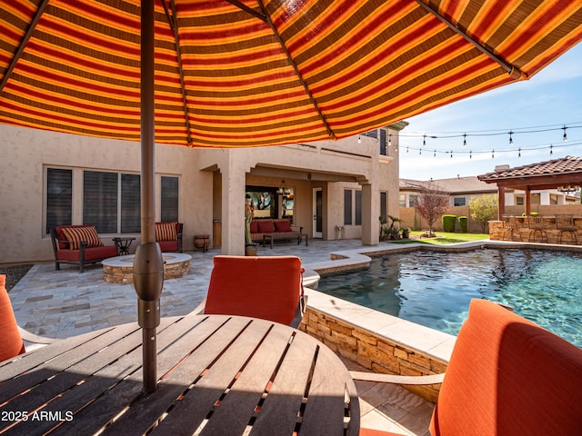 pool with a patio and an outdoor living space with a fire pit