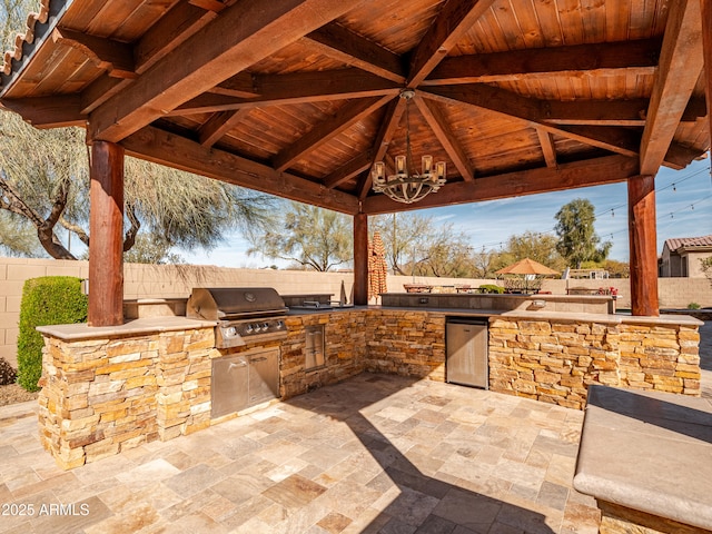 view of patio featuring a gazebo, an outdoor kitchen, a fenced backyard, and a grill