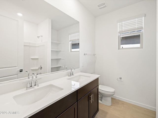 full bathroom with toilet, baseboards, walk in shower, and a sink