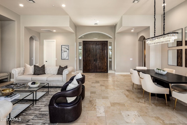 living room with arched walkways, recessed lighting, visible vents, stone finish floor, and baseboards