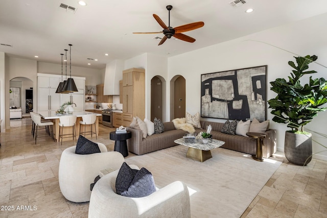 living area with arched walkways, stone tile flooring, visible vents, and recessed lighting