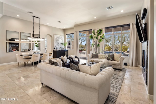 living room with a lit fireplace, visible vents, baseboards, and recessed lighting