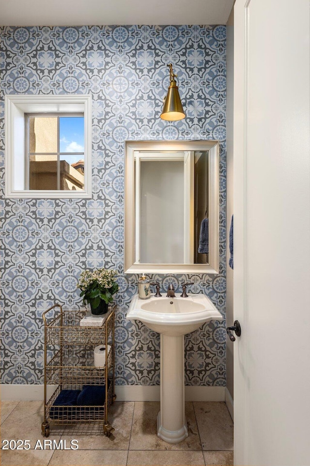 bathroom with tile patterned floors, a sink, baseboards, and wallpapered walls