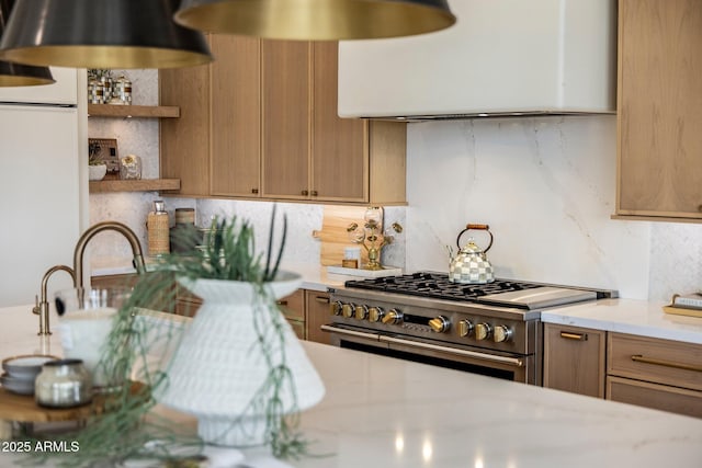 kitchen featuring tasteful backsplash, brown cabinetry, light countertops, high end stove, and open shelves