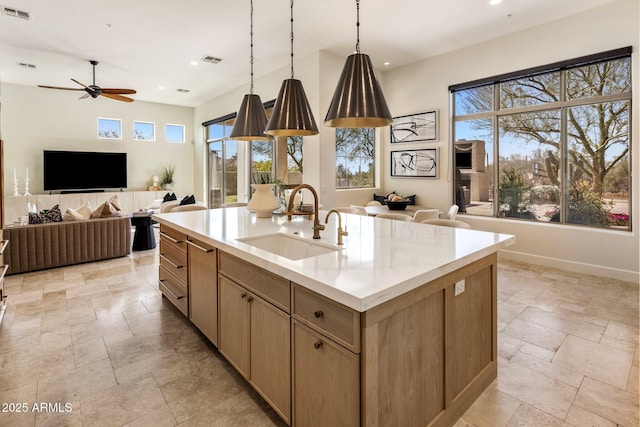 kitchen with stone tile floors, visible vents, open floor plan, and a sink