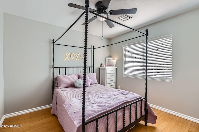 bedroom with visible vents, ceiling fan, baseboards, and wood finished floors