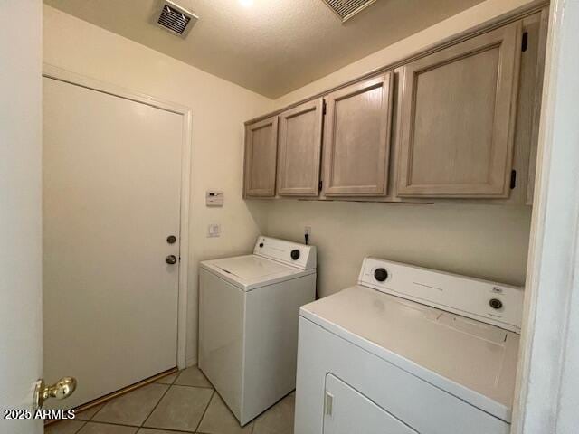 washroom featuring cabinets, light tile patterned floors, and washer and clothes dryer